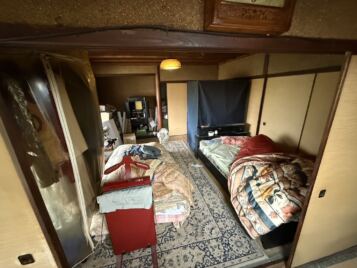 美馬市O様邸の遺品整理。奥の部屋に設置されたベッドや仏壇、衣類などが残っている様子(Before)。